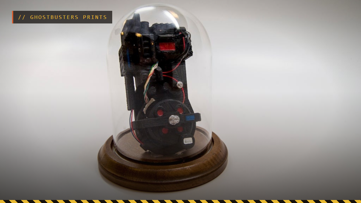 A 3D printed miniature Ghostbusters proton pack under a glass dome, by TheNewHobbyist