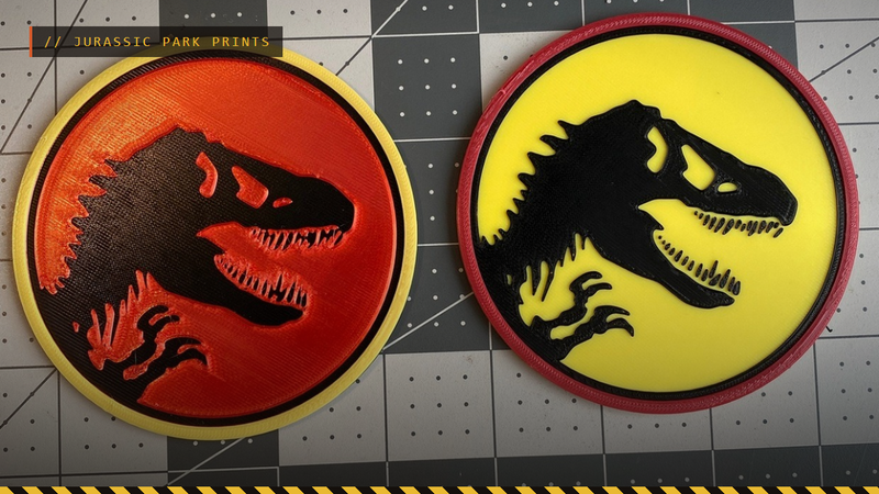 Two 3D printed Jurassic Park logo coasters, one red and one yellow, by nerdyviews