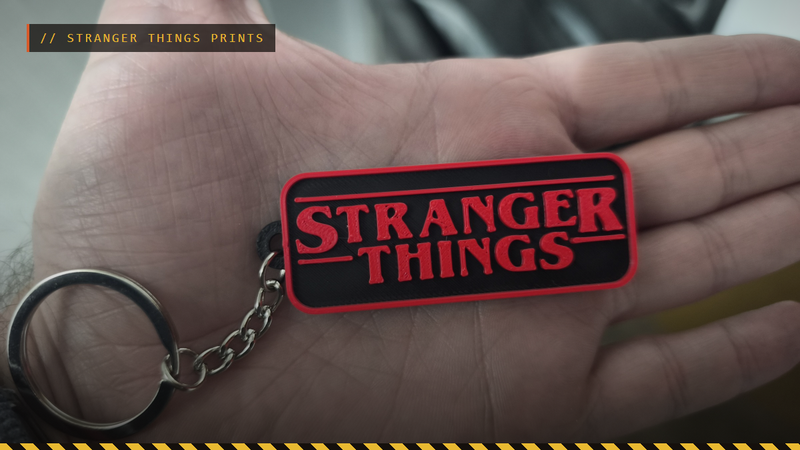A hand holding a 3D printed red and black Stranger Things keychain, by Fernando Ureña Herrero