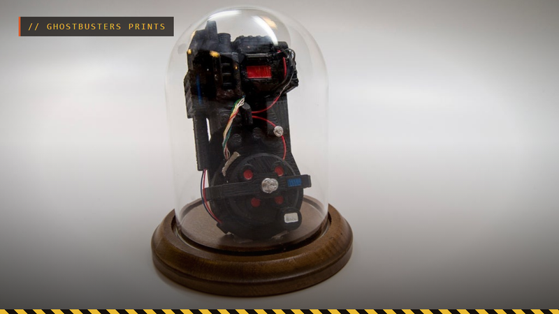 A 3D printed miniature Ghostbusters proton pack under a glass dome, by TheNewHobbyist