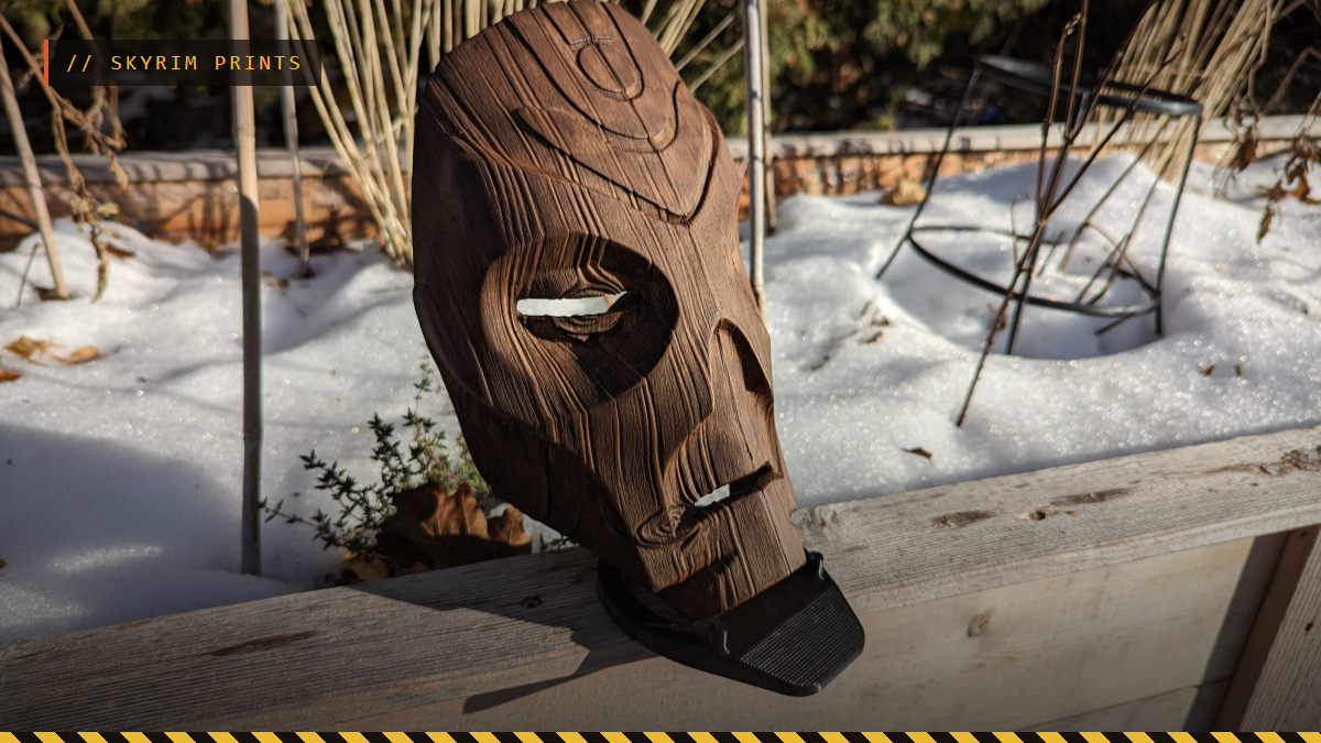 A 3D printed Skyrim Dragon Priest mask with a wood finish on a stand, by Garyu